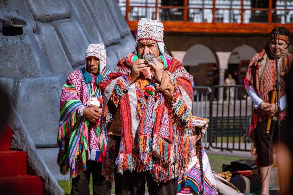 Traditional Andean musicians in colorful ponchos performing during Inti Raymi, the Incan Sun Festival in Cusco, Peru