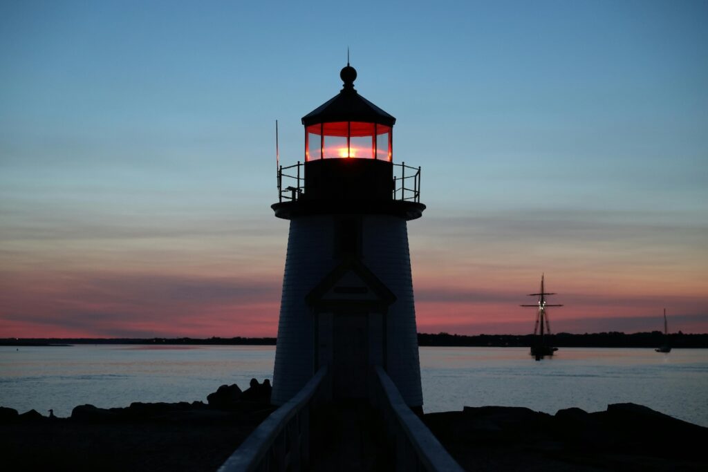 Lighthouse at sunset with boats in the background in Nantucket, Massachusetts