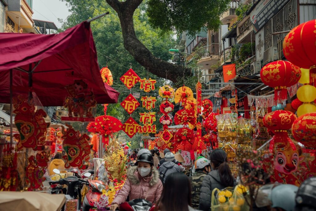 Crowded street market in Vietnam decorated with red and gold banners and lanterns for Tết Nguyên Đán, the Vietnamese Lunar New Year