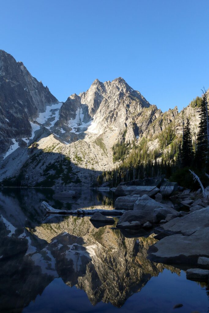 A mountain with snow on it surrounded by trees and reflected in a lake in Leavenworth, Washington on a sunny day