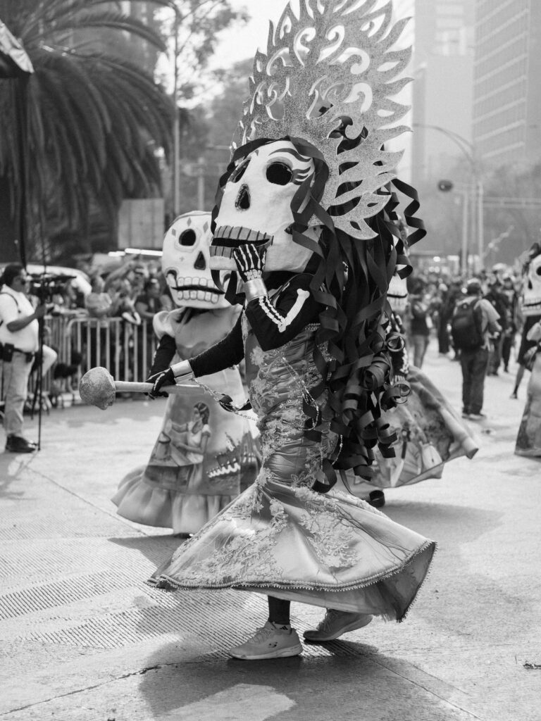 People in traditional Day of the Dead costumes and skull masks during a Dia de los Muertos parade in Mexico.