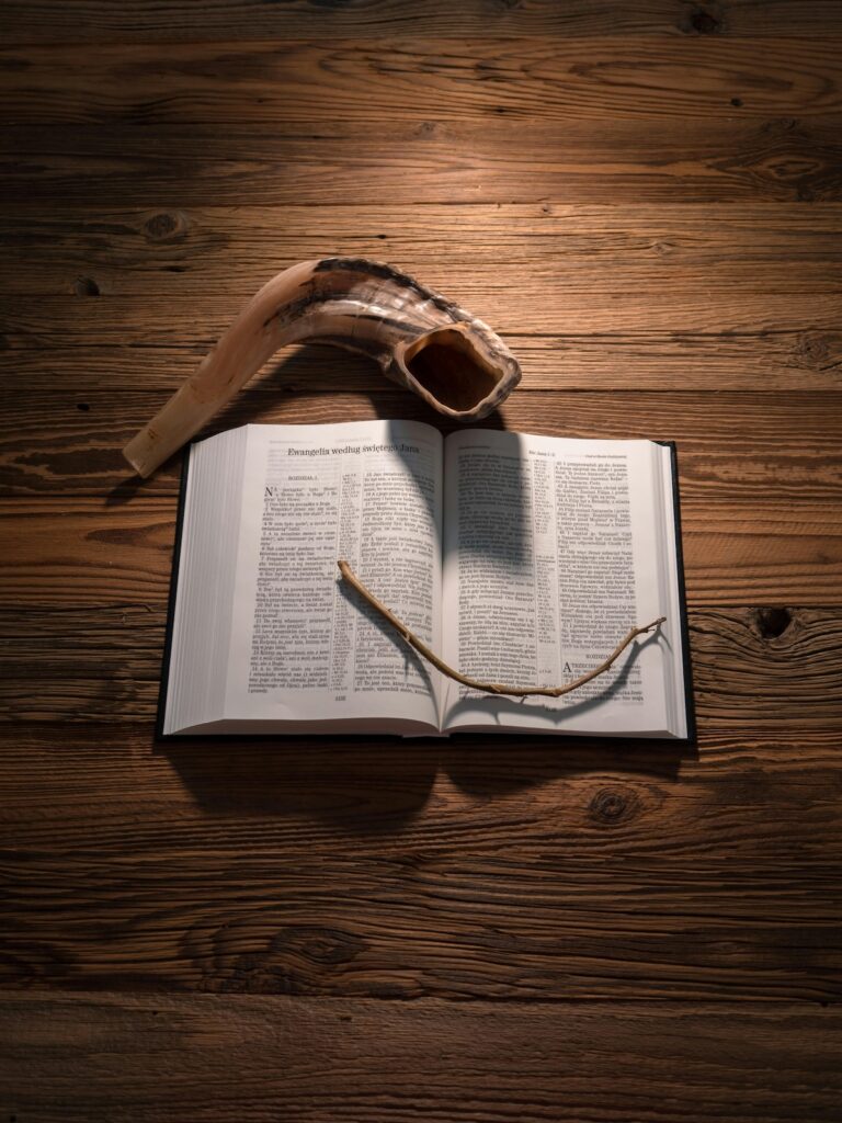 Shofar resting on an open Torah scroll on a wooden table, representing Jewish High Holidays like Rosh Hashanah and Yom Kippur.