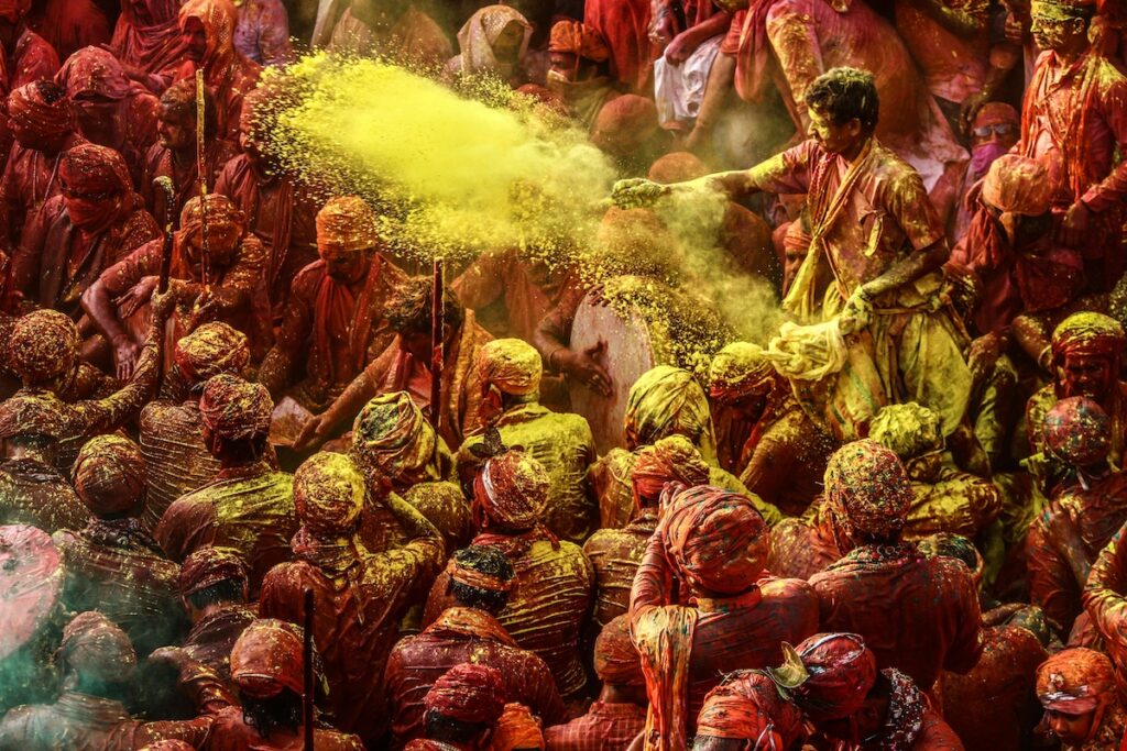 Crowd of people throwing yellow powder during Holi festival in India, celebrating the arrival of spring