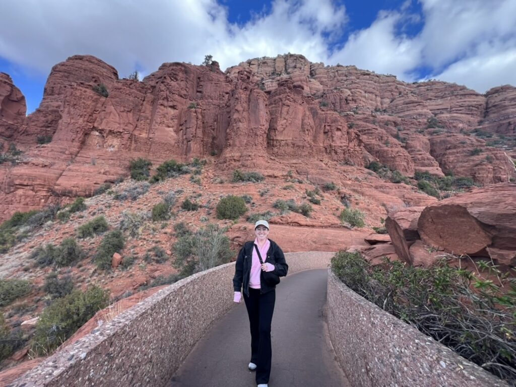 Sarah in Sedona, AZ near the chapel of the Holy Cross with red rocks behind her.